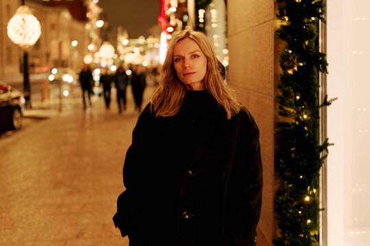 Person Stands in City Street During Evening With Festive Lights