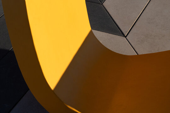 Yellow Curved Structure with Geometric Shadow and Tiled Surface
