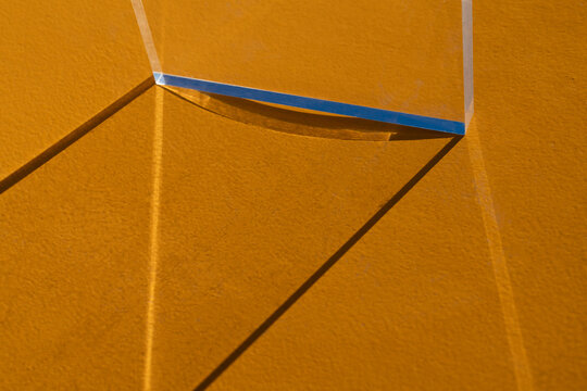 Glass Prism Edge Casting Geometric Shadows on Yellow Surface