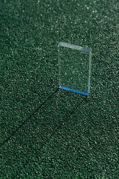 Glass Prism Standing on Green Textured Asphalt Surface