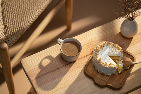Coffee and cake on a wooden table with a woven chair in the background