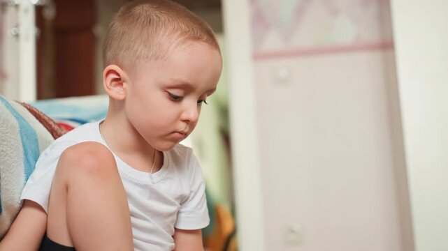 Young boy carefully stacking play blocks peacefully. Serene child engrossed in assembling toy pieces silently. Peaceful boy with thoughtful expression carefully stacking colorful toy blocks indoors