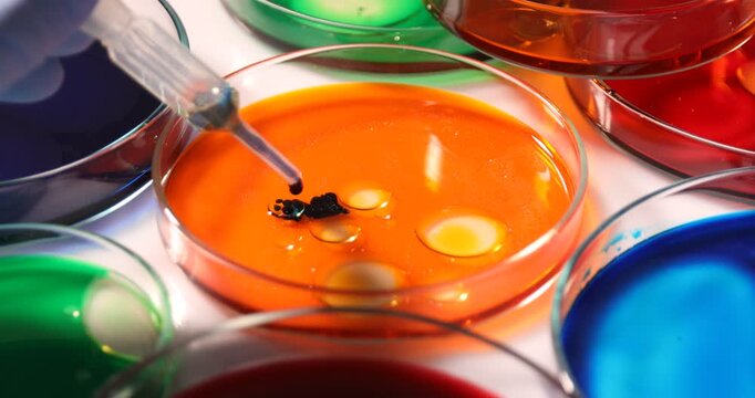 Scientist dripping reagent into Petri dish with sample at white table, closeup