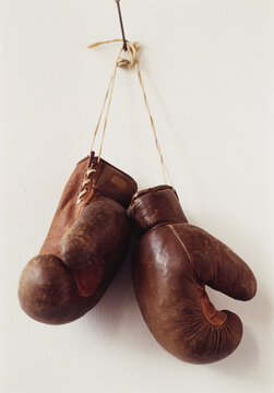 Vintage Boxing gloves hang on a nail against a plain wall