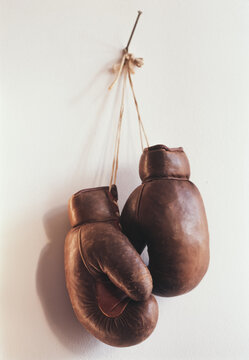 Vintage Boxing gloves hang on a nail against a plain wall
