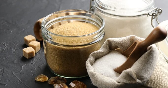 Different types of sugar on black table, spinning