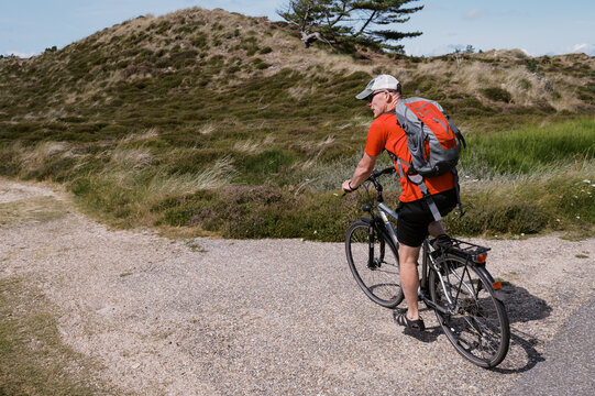 man riding bike among dunes in denmark
