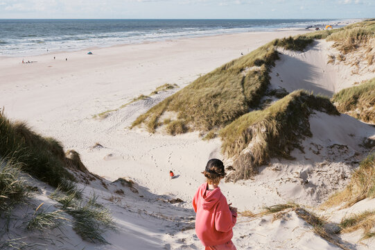 boy on top of huge dune in b&oslash;rsmose denmark looking at sister