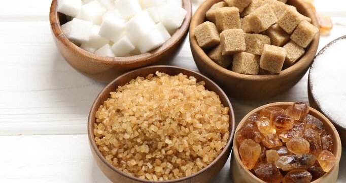 Different types of sugar on white wooden table, closeup