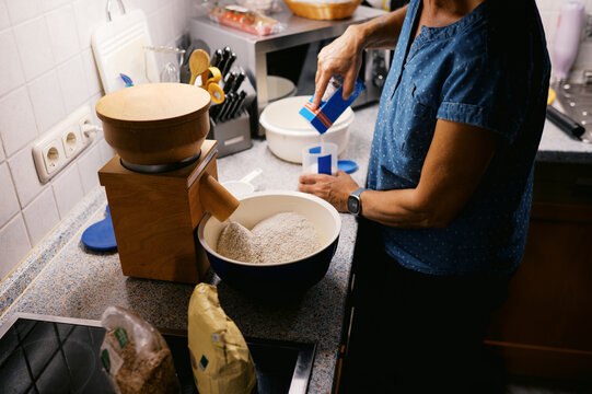woman milling wheat into flour at home in kitchen 