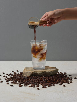 Pouring Coffee Into Ice Water Over Coffee Beans in Studio Shot