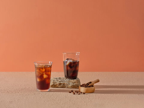 Two Glasses of Iced Coffee With Coffee Beans on Orange Background