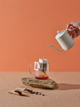 Pouring Hot Water Over Coffee in Dripper Setup on Rustic Surface