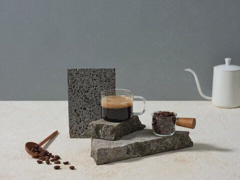 A creative presentation of black coffee, coffee beans over stones