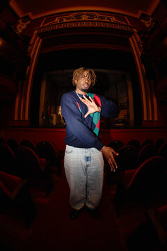 Dancer performs in theater with red seats and bright stage light