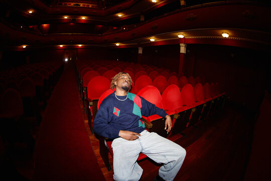 Music artist relaxes in empty theater seats during sound check