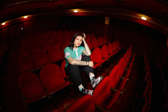 Person sitting alone in a red theater during evening hours