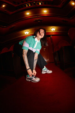 Person ties shoes inside a theater with red walls and lights