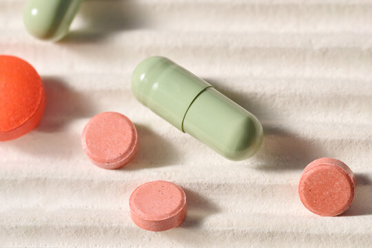 Tablets and a capsule are scattered on a light-colored surface