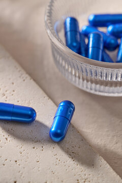 Vibrant blue capsules spilling from a glass bowl