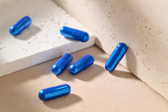 Scattered shiny blue capsules displayed on textured surfaces