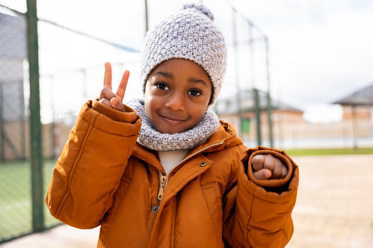 Happy child making peace sign in winter clothes