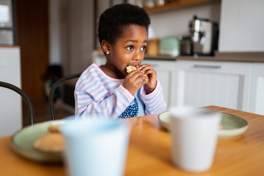 Young black girl eating snack for breakfast in kitchen