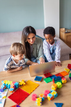 Mother homeschooling diverse children using laptop at home