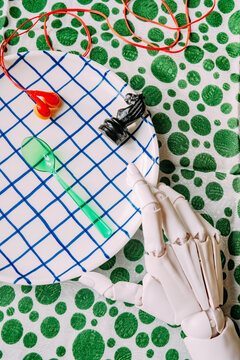 Hand with a green spoon on a plate with small objects