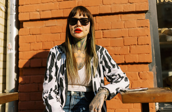 Woman With Tattoos Sits Outside a Cafe in the Sun