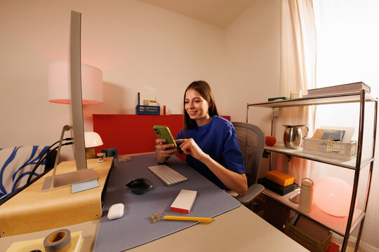 Businesswoman using smartphone at home office workspace