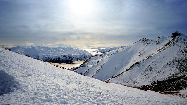 Paysage hivernal enneig&eacute; avec vue sur un lac et vall&eacute;e depuis les hauteurs des Alpes du Sud, &icirc;le du Sud, Nouvelle-Z&eacute;lande, soleil voil&eacute;