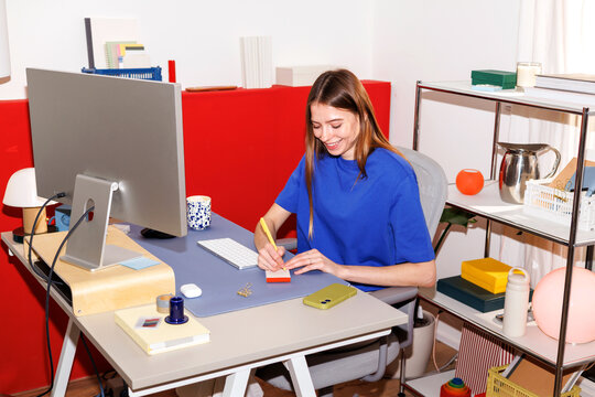 Woman in Business Taking Notes at Modern Desk with Flash 