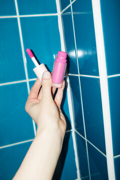 Hand holsding bright baby pink makeup beauty product blush in bathroom