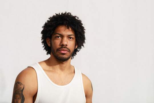 Man With Curly Hair Poses Against Plain Background in Studio