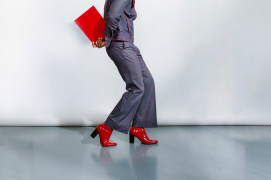 Person Walks in High Heels Holding Red Folder in Studio Setting