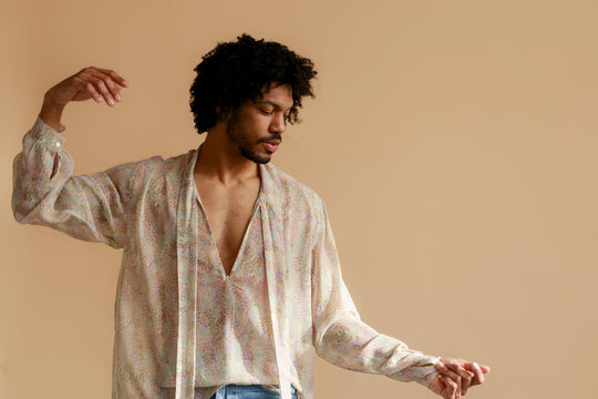 Man Wearing Light Patterned Shirt Poses in a Simple Room