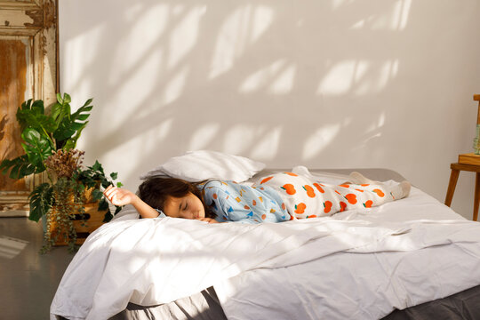 Child Sleeping on a Bed With Shadows on the Wall 
