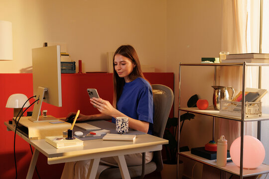 Woman Embracing Lifestyle with Smartphone at Home Office Desk