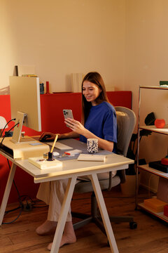 Person using smartphone at modern home workspace