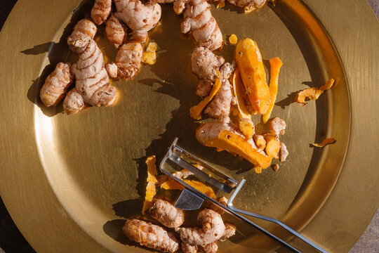 Fresh Turmeric Root With Peels on a Gold Plate During Daylight