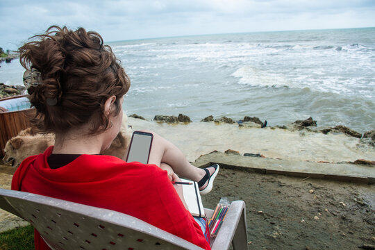 Woman Sitting by the Sea Drawing With Colored Pencils