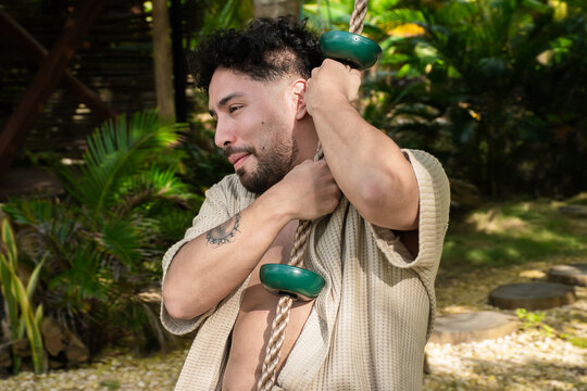Man Swings on Rope in a Green Garden During Daylight Hours