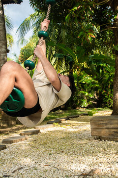 Man Swings on Rope in a Green Garden During Daylight Hours