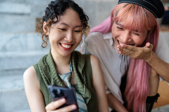 Two friends laughing at something on a phone.