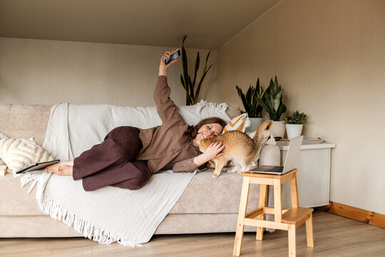 A woman making selfie with her cat at home by smart phone.