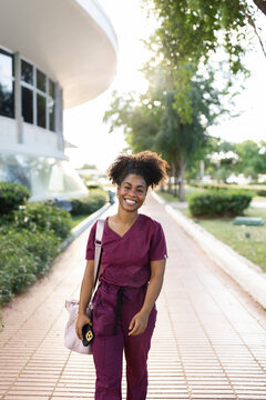 Young Female Doctor Walking Outside in Scrubs Near Hospital