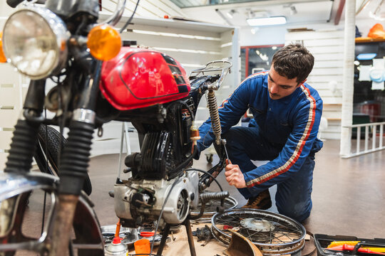 Young Mechanic Working on Red Vintage Motorbike Restoration