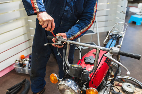 Mechanic Repairing Vintage Motorcycle Handlebars in Garage