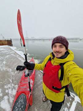 Adventurer Standing with Kayak and Paddle in Snowy Winter Landscape
